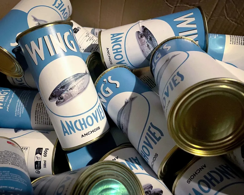 A crate of fictional Wings anchovy tins with engraved airship labels.