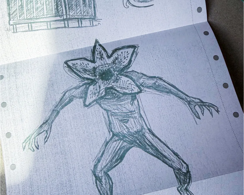 Green-ink sketch of a Demogorgon creature on lined notebook paper.