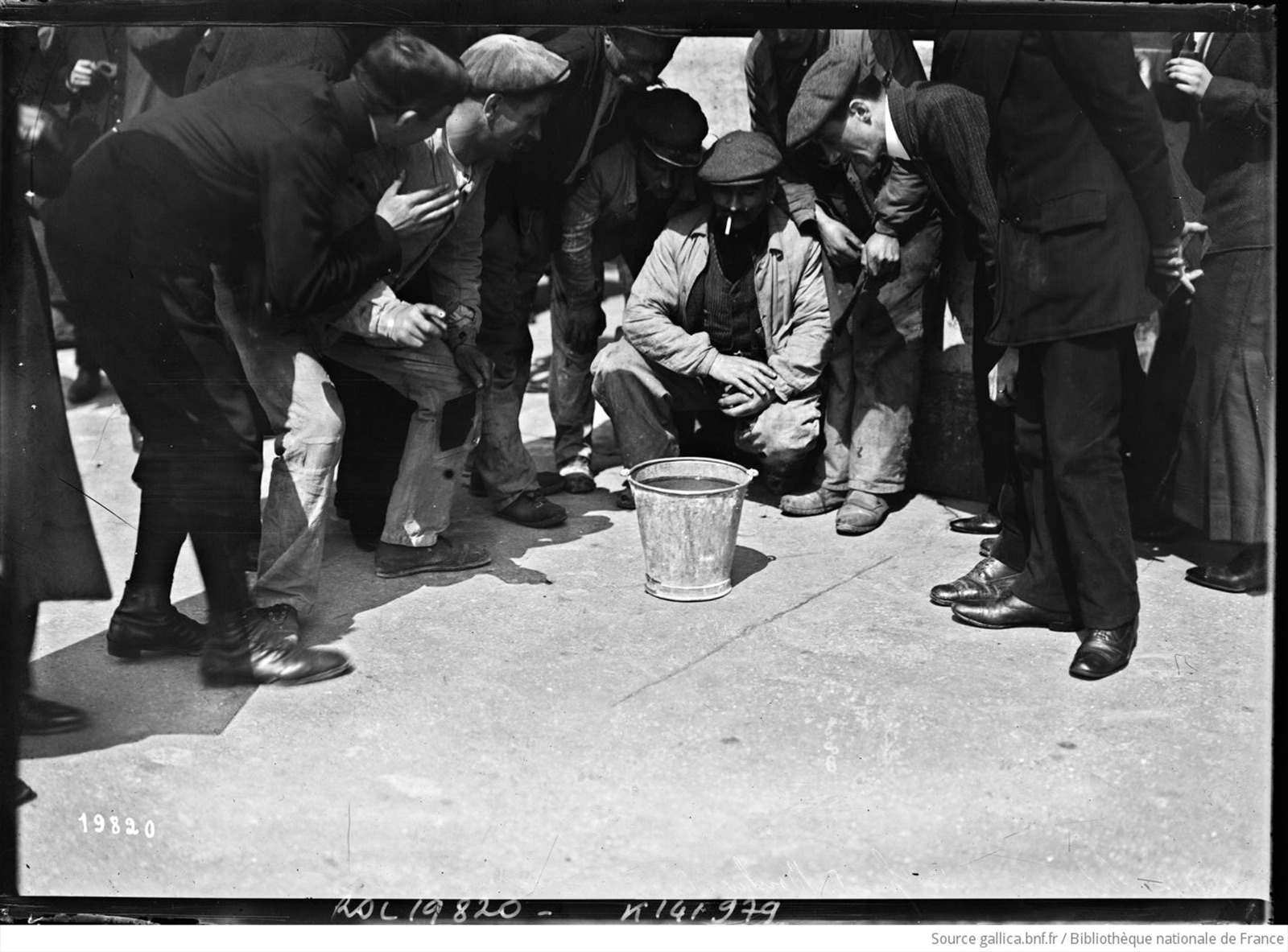 April 17, 1912, solar eclipse in Paris, Grands Boulevards, people gathered and looking into a bucket of water. Press photograph, Agence Rol.